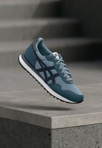 Mėlynos ir pilkos sportinės kedai su tekstiline ir sintetine viršūne, su raišteliais, trimis juostelėmis ir tekstūruotu gumuotu padu.