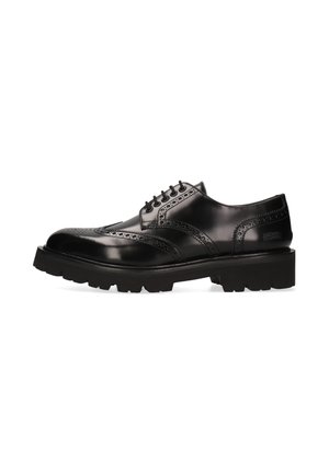Schwarzer Leder-Brogue-Schuh mit Flügelkappendesign, perforierten Details, schwarzen Schnürsenkeln und dicker profilierter Sohle auf weißem Hintergrund.