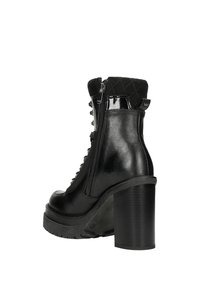 Stivaletto nero con tacco, caratterizzato da una finitura lucida in patent, un polsino testurizzato, zip laterale e design con lacci e occhielli metallici. Suola piatta spessa.