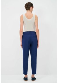Marineblauwe op maat gemaakte broek met een slim fit en plooi-details, gecombineerd met een lichtgrijze tanktop. Beschikt over een achterzak en een subtiele tailleband.