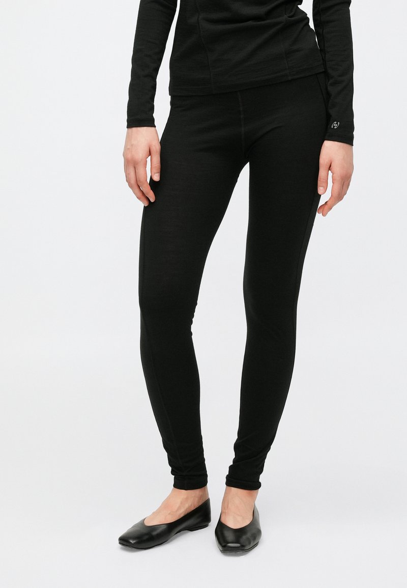 Colanți negri mulați, cu textură netedă și talie elastică. Purtați cu pantofi negri simpli, fără toc. Fără modele sau accente vizibile.