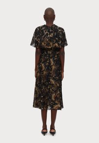 Vestito nero con una silhouette fluida, maniche corte a sbuffo e un motivo floreale in tonalità dorate, arancioni e marroni. Tessuto leggero.
