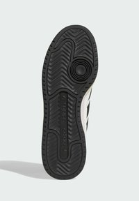 Black rubber sole with textured grooves and circular design. Features Adidas branding and tapered edges. Predominantly flat with minimal elevation.