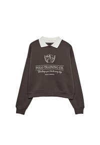 Felpa cropped marrone scuro con colletto bianco a polo, testo bianco frontale e simbolo di un cavaliere a cavallo con la scritta "Polo Training Co. Sfida i tuoi limiti ogni giorno."