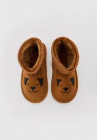 Bruna plyschtofflor med ett hundansikte-design; mjuk textur, vikbar manschett, svarta öron och nos, samt broderade kantdetaljer.