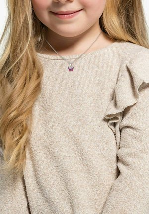 Silberne Halskette mit einem kleinen Schmetterlingsanhänger mit rosa Akzenten, getragen über einem hellbeigen, strukturierten Pullover mit Rüschensäumen.