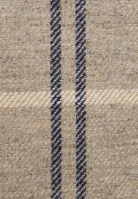 Tissu en laine présentant un motif pied-de-poule beige et gris avec des rayures noires. Texture douce avec une légère brillance, mettant en valeur les détails tissés.