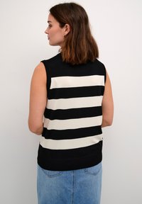 Sleeveless, black and white striped knit top with a smooth texture, featuring a high neckline and a solid black hem at the bottom.