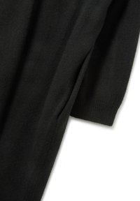 Maglione nero in maglia con maniche lunghe, polsini a costine e una texture morbida, arricchito da una fessura laterale per un tocco di stile.