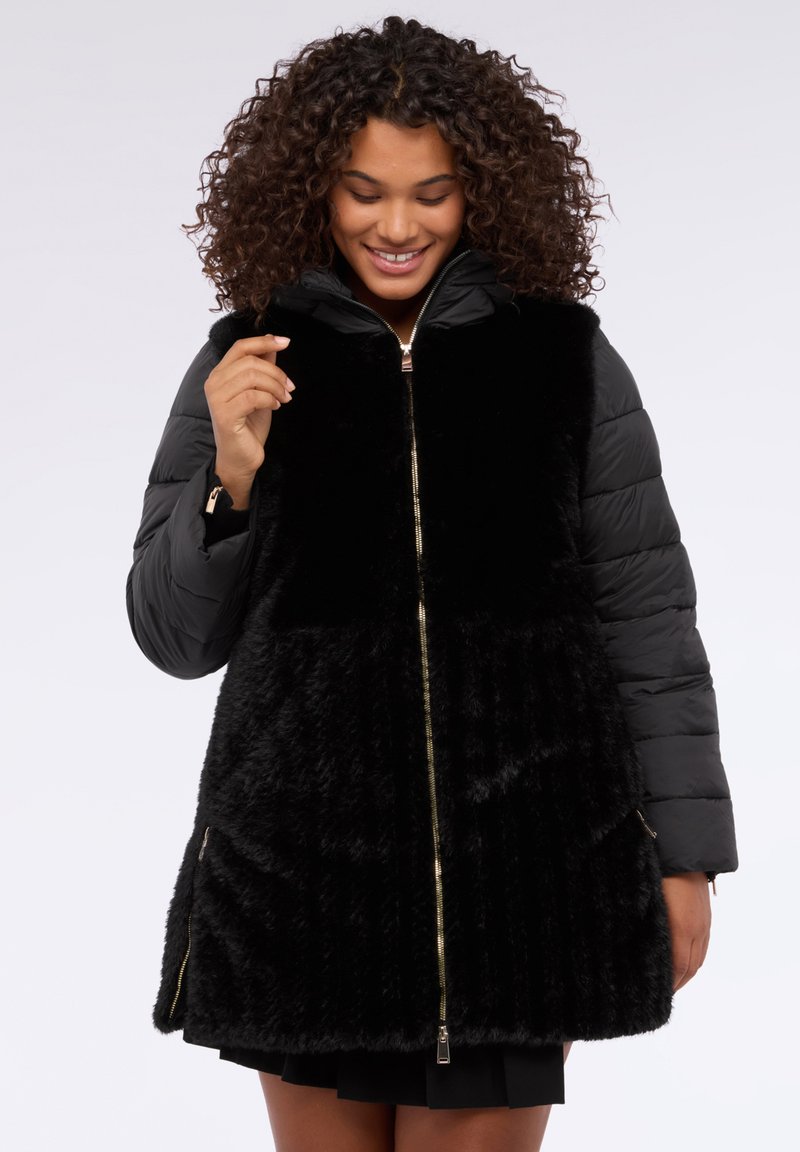 Abrigo acolchado negro con frente de piel sintética, cremallera dorada y bolsillos laterales. Cuenta con mangas acolchadas y capucha, que ofrecen calidez y contraste de texturas.