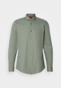 Groen langemouwenshirt van gladde stof, met een knoopsluiting aan de voorkant, een puntig kraag en zwarte knopen langs de knoopsluiting.