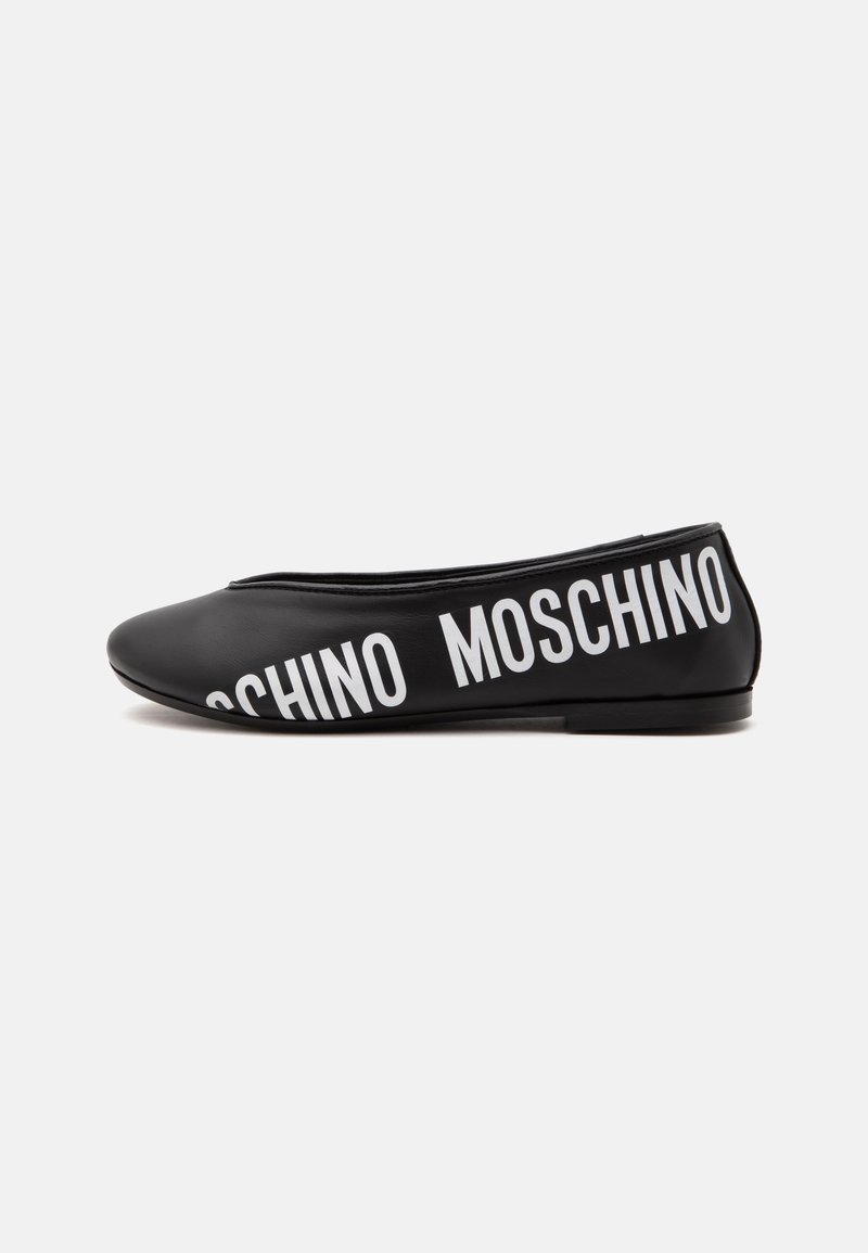 Chaussure plate noire avec un bout arrondi et texte blanc MOSCHINO imprimé en diagonale sur le côté.