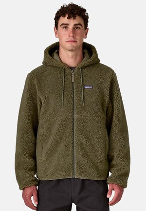 Giacca in pile verde oliva con superficie texture e morbida, chiusura a zip, cappuccio regolabile e tasca frontale. Presenta dettagli grigi sulla zip.
