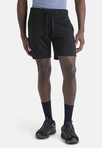 Pantalones cortos negros con cintura elástica y cordón, hechos de una tela suave. Combinados con zapatillas deportivas negras y calcetines azul marino.