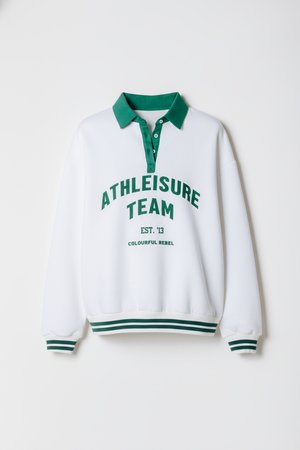 White pullover sweatshirt with green collar and accents. Text reads "ATHLEISURE TEAM EST. 13 COLOURFUL REBEL." Features ribbed cuffs and hem.