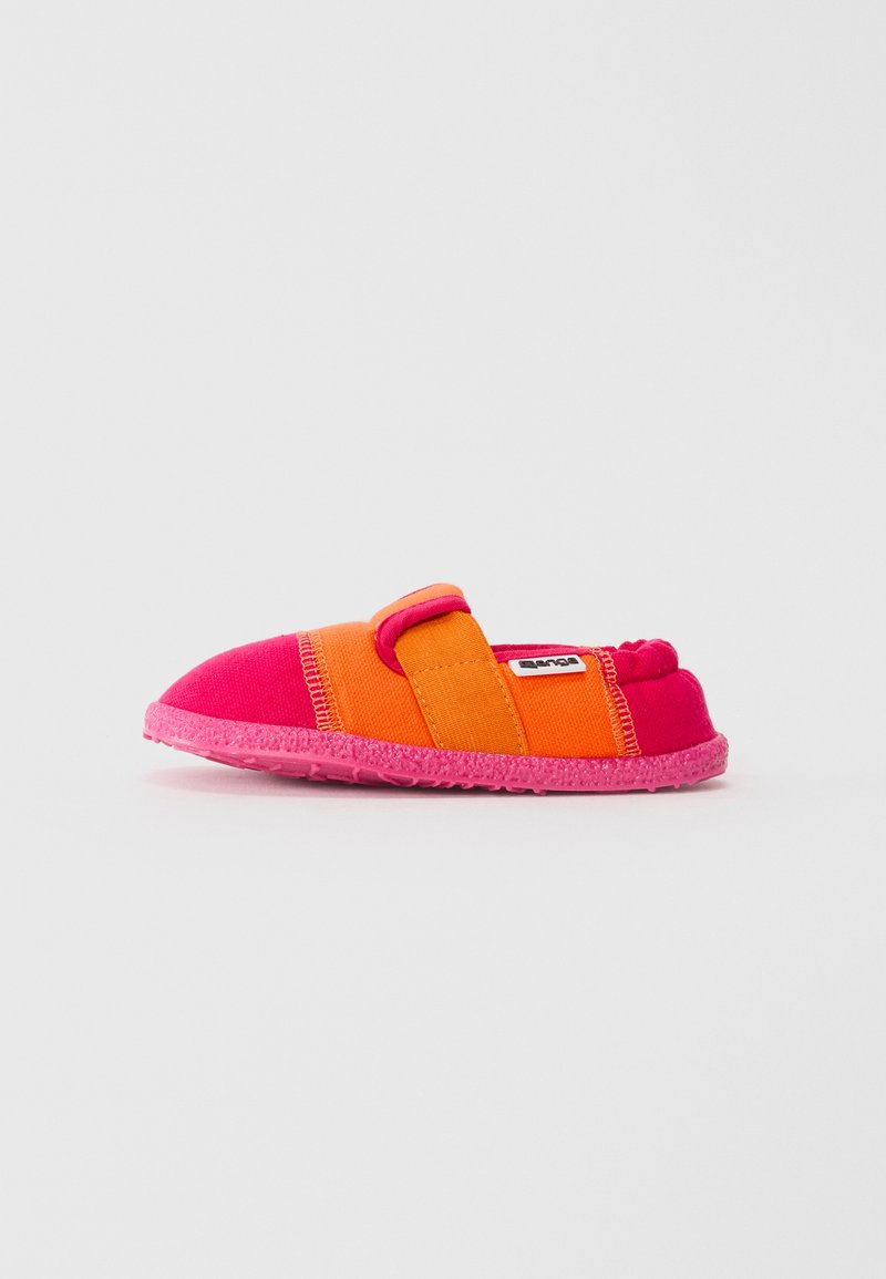 Bērna slip-on kurpes rozā un oranžā audumā ar regulējamu siksniņu un teksturētu gumijas zoli, rādītas profilā uz baltā fona.