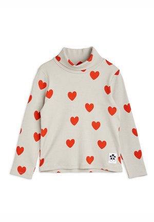 Chemise col roulé beige clair à manches longues avec des motifs de cœurs rouges et un petit patch logo panda près de l'ourlet.