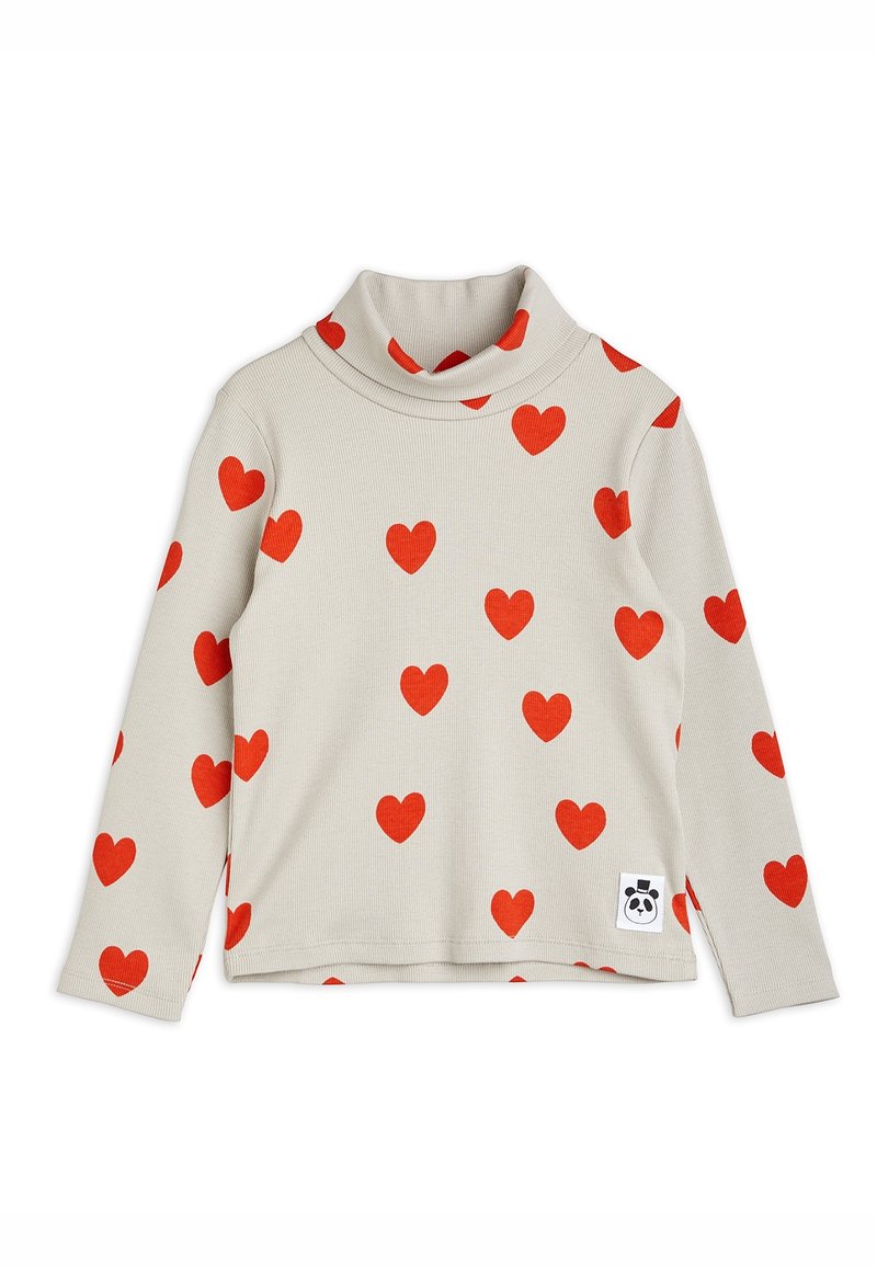 Chemise col roulé beige clair à manches longues avec des motifs de cœurs rouges et un petit patch logo panda près de l'ourlet.