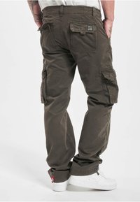 Mørkegrønne cargobukser i bomull med avslappet passform, utstyrt med flere lommer og en merkelapp på midjebåndet. Style med hvite joggesko.