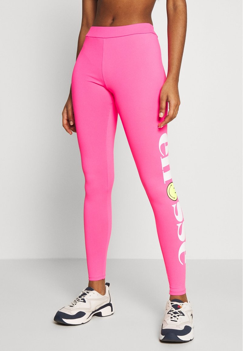 Różowe legginsy z elastycznego materiału mają wysoki pas, nadrukowany tekst na boku oraz akcent w postaci żółtej buźki.