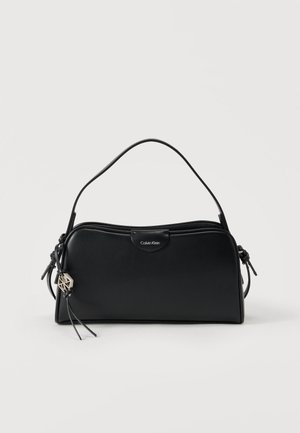 Black leather handbag with a structured design, featuring a short handle, zip closure, and metal logo accent. Decorative tassel attached.