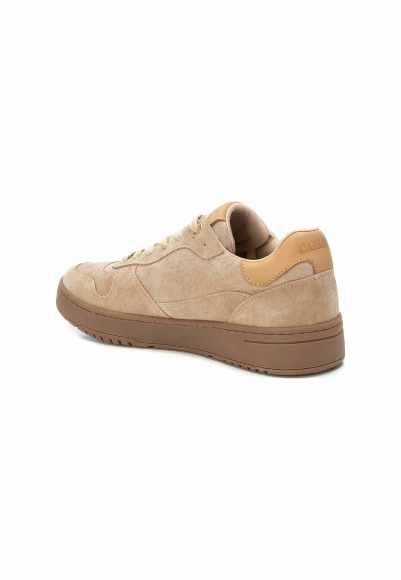 Baskets en suède beige avec semelle en caoutchouc marron clair, design à lacets et accent en cuir tan au niveau du talon, positionnées à un léger angle arrière sur le côté.
