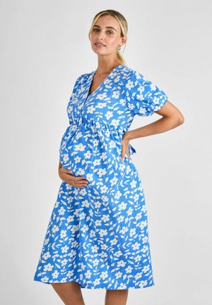Blue floral maternity dress with puff sleeves, a V-neckline, gathered waist, and knee-length hem. Features white flower patterns throughout.