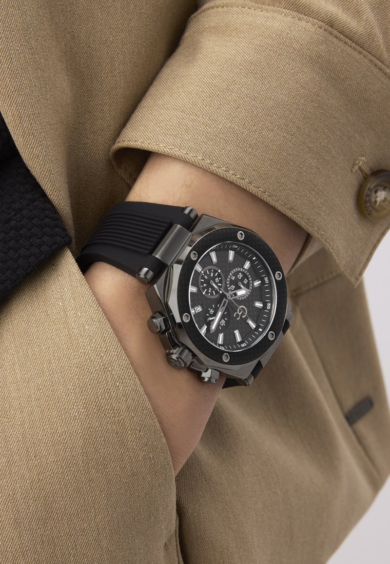 Czarny zegarek z teksturowanym czarnym paskiem z gumy, sześciokątną srebrną kopertą i czarną tarczą z srebrnymi akcentami oraz funkcjami chronografu.
