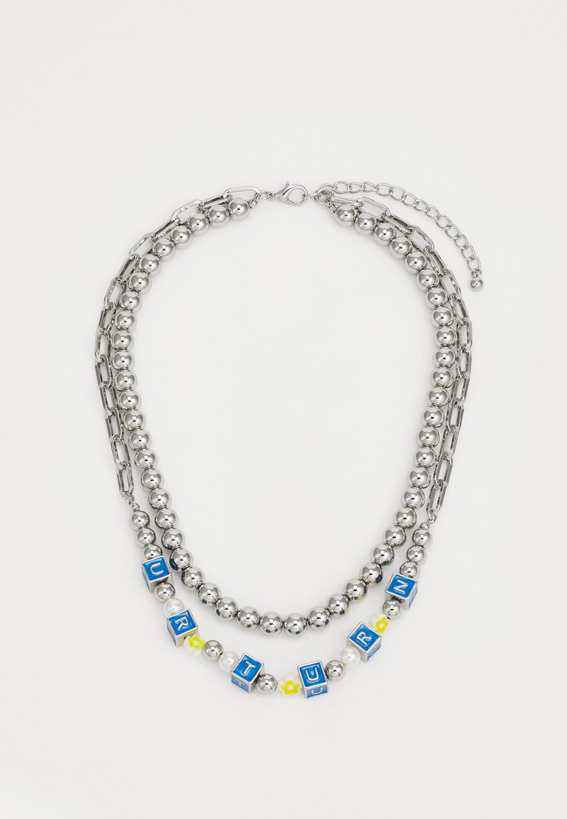 Stříbrný náhrdelník s řetízky v dvou vrstvách, kulatými perlami, modrými písmenkovými kostkami a květinovými akcenty. Obsahuje karabinku a nastavitelný řetízek.