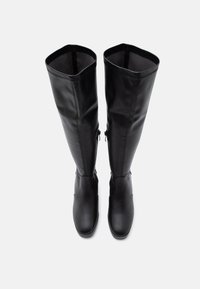 Bottes hautes en cuir noir dépassant le genou avec un design élégant et ajusté ; texture lisse et quincaillerie minimaliste ; bout arrondi et semelle plate.