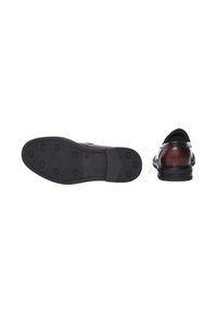 Scarpa elegante in pelle nera con finitura liscia, punta chiusa e forma arrotondata. La suola in gomma presenta un motivo a grip circolare e un tacco piatto.
