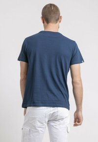 T-shirt en coton bleu marine à manches courtes et col rond, avec un design uni et une petite étiquette logo sur la manche droite.