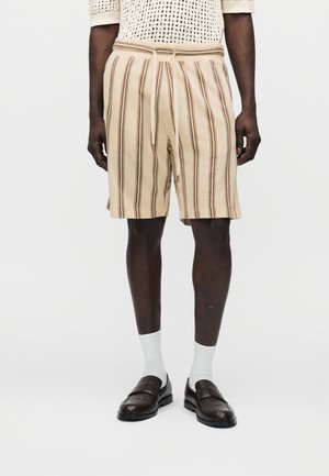 Beige korte broek met verticale bruine strepen, voorzien van een elastische tailleband en een koordsluiting, met een gestructureerde stof en een losse pasvorm.