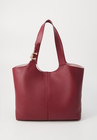 Rød læder tote taske med en struktureret overflade, bred åbning, korte håndtag og en guld detalje på siden. Enkel og funktionel design.