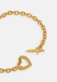 Gold chain bracelet featuring oval links, a heart-shaped centerpiece, and a decorative sword charm. Smooth texture and polished finish.