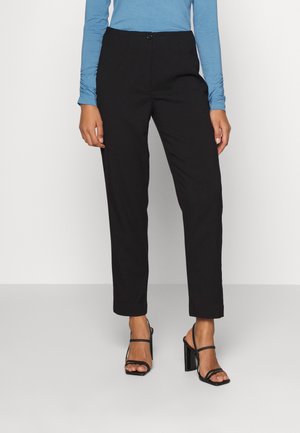 Pantalons noirs à coupe droite avec un devant plat, dotés d'une fermeture à un bouton, associés à un haut à manches longues bleu clair et des talons noirs à lanières.