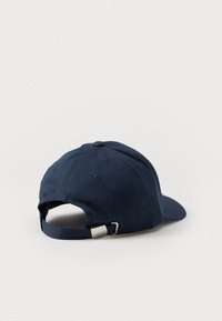 Marineblå baseball cap med buet skjerm, justerbar stropp bak og et metallisk logo-natur. Laget av holdbart stoff.