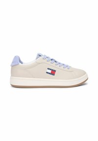 Baskets beige basses avec lacets violets clairs et languette au talon, semelle blanche, et logo Tommy Jeans sur le côté.