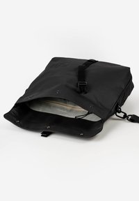 Zaino nero con esterno impermeabile, tracolla regolabile e tasca interna con zip. Presenta bottoni a pressione e un design semplice.