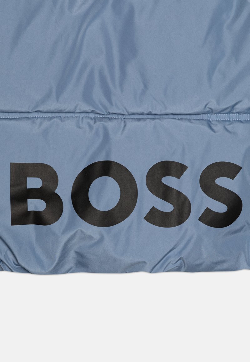 Tissu rembourré bleu clair avec un grand texte noir "BOSS". Texture lisse avec un léger éclat et des détails de couture horizontale.