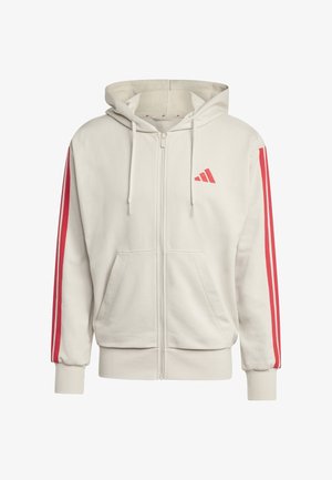 Sweat à capuche beige zippé avec logo Adidas rouge sur la poitrine, bandes rouges sur les manches, poches avant et capuche avec cordon de serrage.