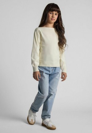 Pull à manches longues, col rond en crème clair, associé à un jean décontracté bleu clair et des baskets blanches avec des accents beige.