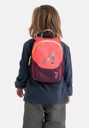 Enfant portant un sac à dos rouge et violet avec des personnages d'animaux, habillé d'une veste bleu foncé et d'un pantalon gris, vu de dos sur fond blanc.