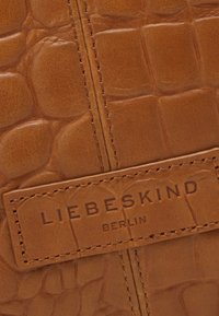 Sac en cuir brun avec un motif crocodile texturé, présentant une couture et une étiquette indiquant "LIEBESKIND BERLIN."