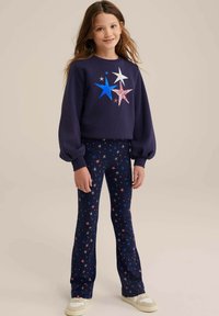 Mornarska majica s kapuco z večbarvnim potiskom zvezd in napihnjenimi rokavi, v kombinaciji z mornarskimi legicami s potiskom zvezd. Obe imata mehak material in elastičen pas.