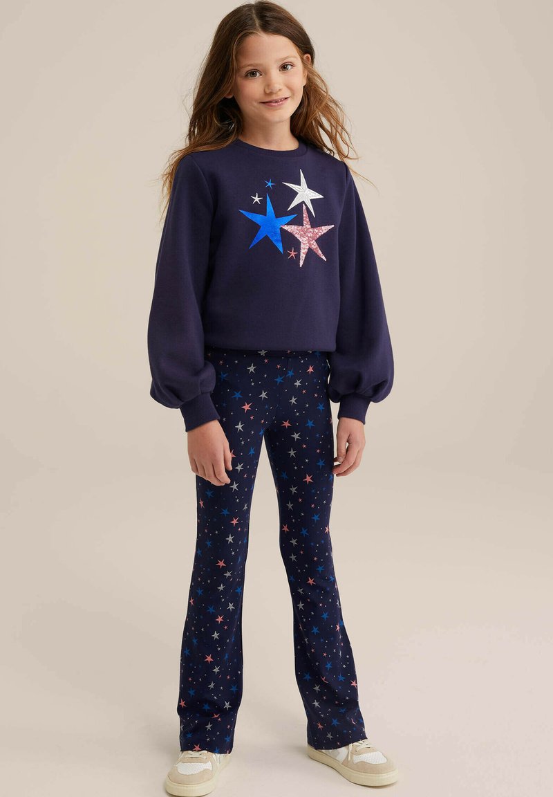Mornarska majica s kapuco z večbarvnim potiskom zvezd in napihnjenimi rokavi, v kombinaciji z mornarskimi legicami s potiskom zvezd. Obe imata mehak material in elastičen pas.