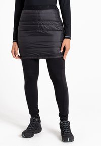 Schwarzer, puffy isolierender Rock mit horizontalen Nähten, kombiniert mit schwarzen Leggings und robusten schwarzen Wanderstiefeln mit blauen Akzenten.