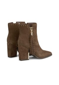 Botas de tobillo de ante marrón con punta afilada, tachuelas decorativas, cremallera lateral y un adorno de borlas en la parte trasera. Diseño de tacón grueso.