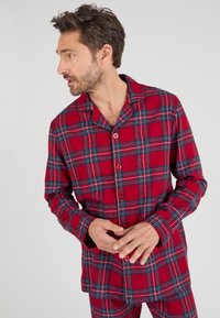 Set di pigiama a quadri rossi con maniche lunghe, camicia con bottoni e pantaloni abbinati. Presenta accenti blu e bianchi nel motivo. Tessuto morbido.