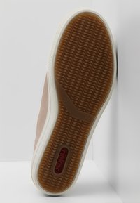 Jasnoróżowy trampek z gumową podeszwą; brązowy, teksturowany bieżnik, biała środkowa część podeszwy oraz czerwone logo na spodzie. Nowoczesny design z gładkim wykończeniem.